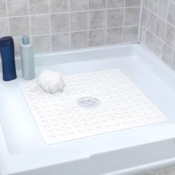 White non-slip shower mat in a shower tray with shampoo bottles and a loofah.
