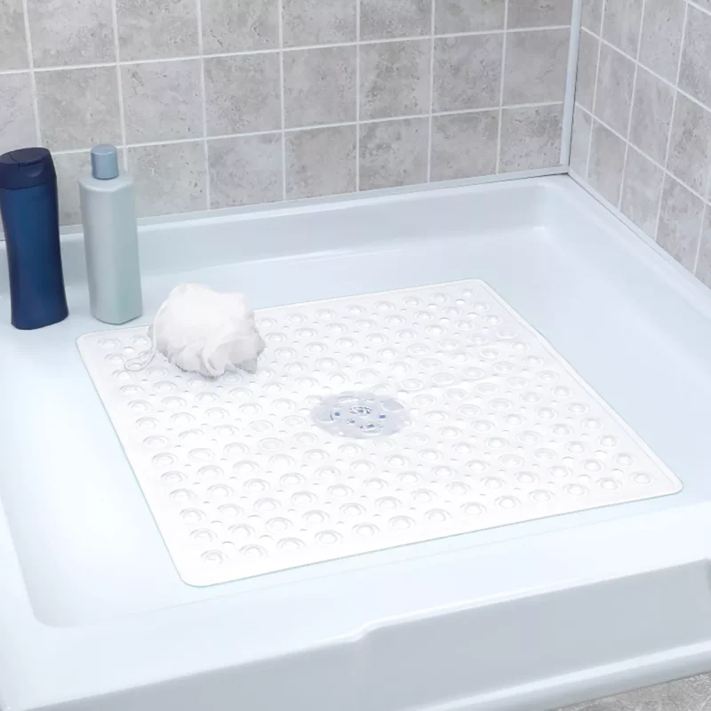 White non-slip shower mat in a shower tray with shampoo bottles and a loofah.