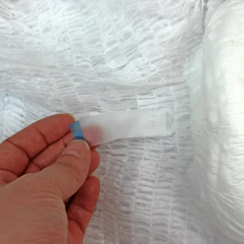Close-up of a hand holding a tab on a textured white pull-up pant.