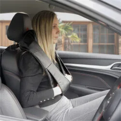 Person using a neck and shoulder massager while sitting in a car.