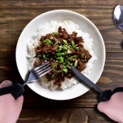 Person using adaptive silverware with straps to eat rice and meat.