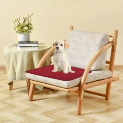Wine red incontinence chair pad on a wooden chair with a puppy sitting on it.