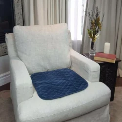 Blue quilted chair pad on a light-colored armchair in a living room.
