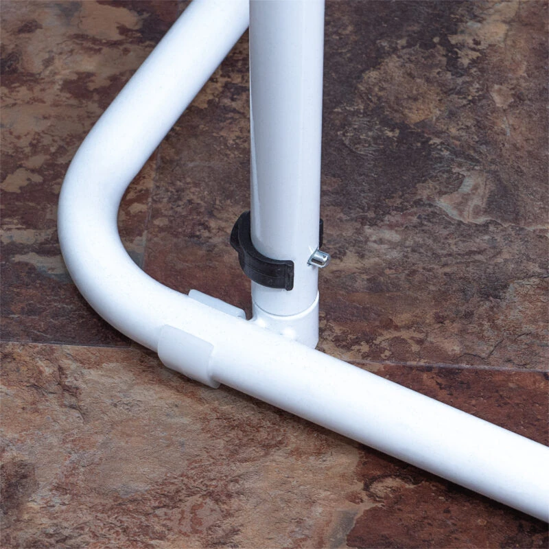 Close-up of the base of an overbed table with a white metal frame on a stone floor.