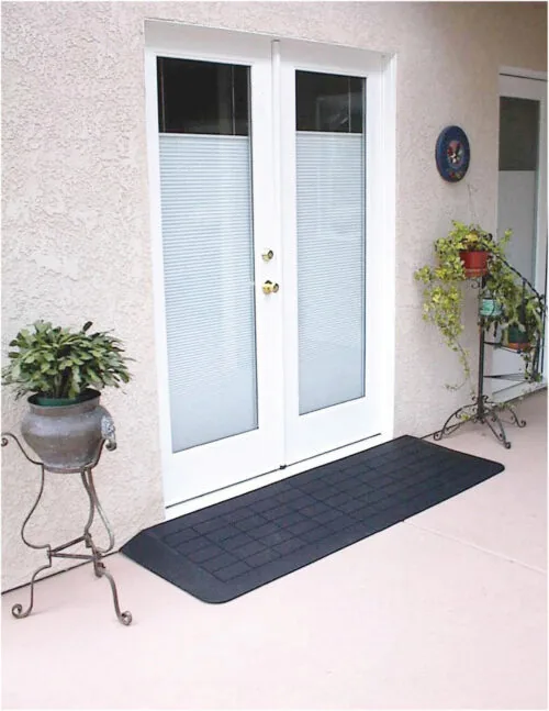 Black accessibility ramp at a white double door entrance.