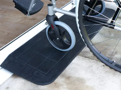Wheelchair on a black threshold ramp at a door entry.