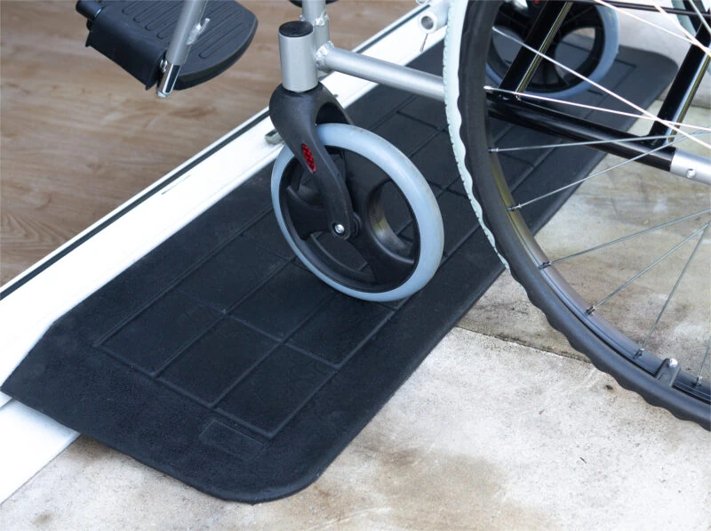 Wheelchair on a black threshold ramp at a door entry.