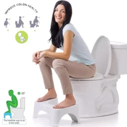 Woman sitting on a toilet using a white foot stool.
