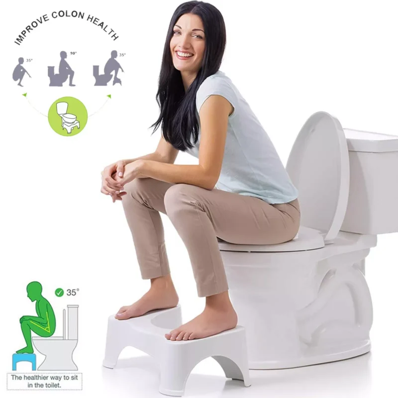 Woman sitting on a toilet using a white foot stool.