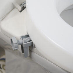 Close-up of a toilet seat extender with a grey bracket attached.