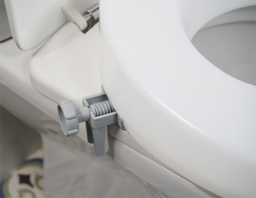 Close-up of a toilet seat extender with a grey bracket attached.