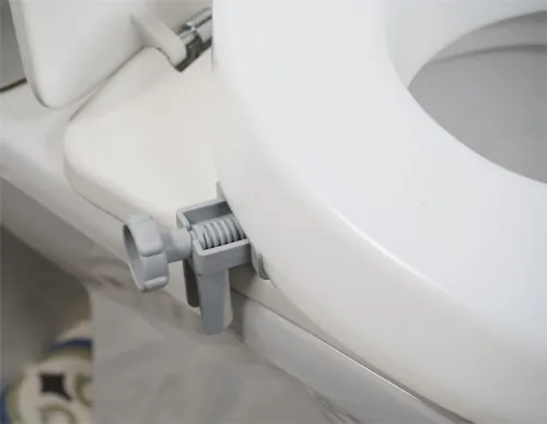 Close-up of a toilet seat extender with a grey bracket attached.