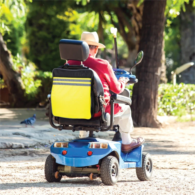 Person on a mobility scooter with a high visibility reflective bag attached.