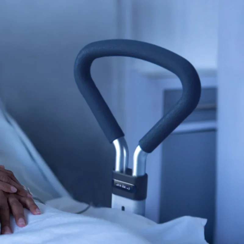 Bed support rail with ergonomic foam grip next to a bed.