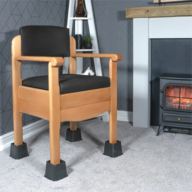 Wooden chair with black cushions elevated on furniture raisers in a living room.