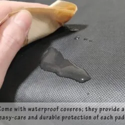 Hand wiping water off a black waterproof cushion cover.