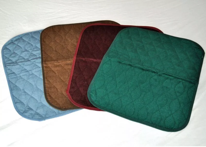 Four incontinence chair pads in blue, brown, burgundy, and green.