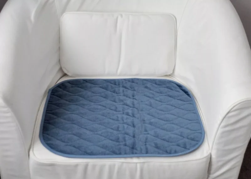 Blue incontinence chair pad on a white chair.