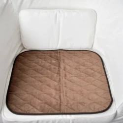 Brown incontinence chair pad placed on a white chair.