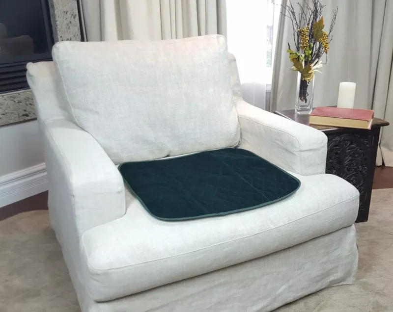 Green incontinence chair pad placed on a white armchair.
