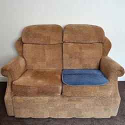 Blue incontinence chair pad placed on a brown sofa.