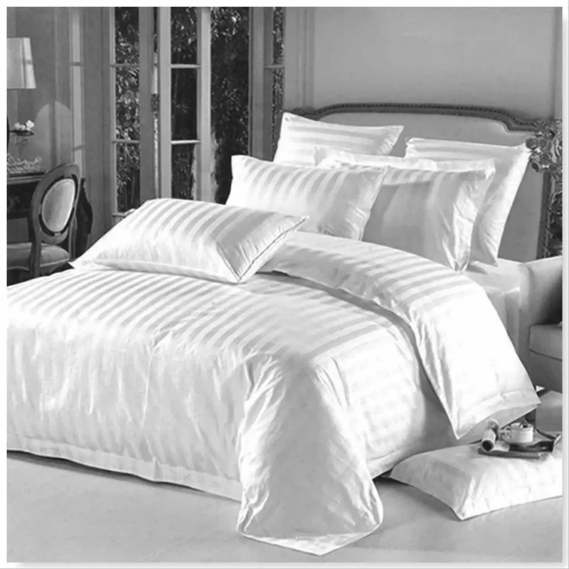 White cotton duvet cover set with pillows on a bed in a bright room.