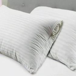 Two white striped pillow covers with zippers on a bed.