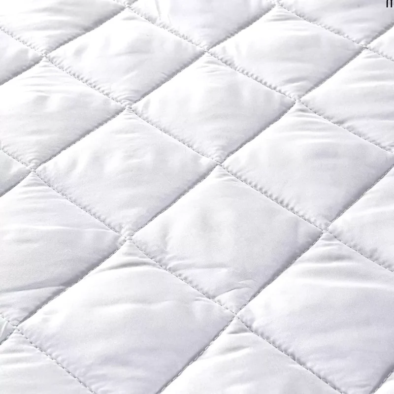 Close-up of a quilted white mattress protector.