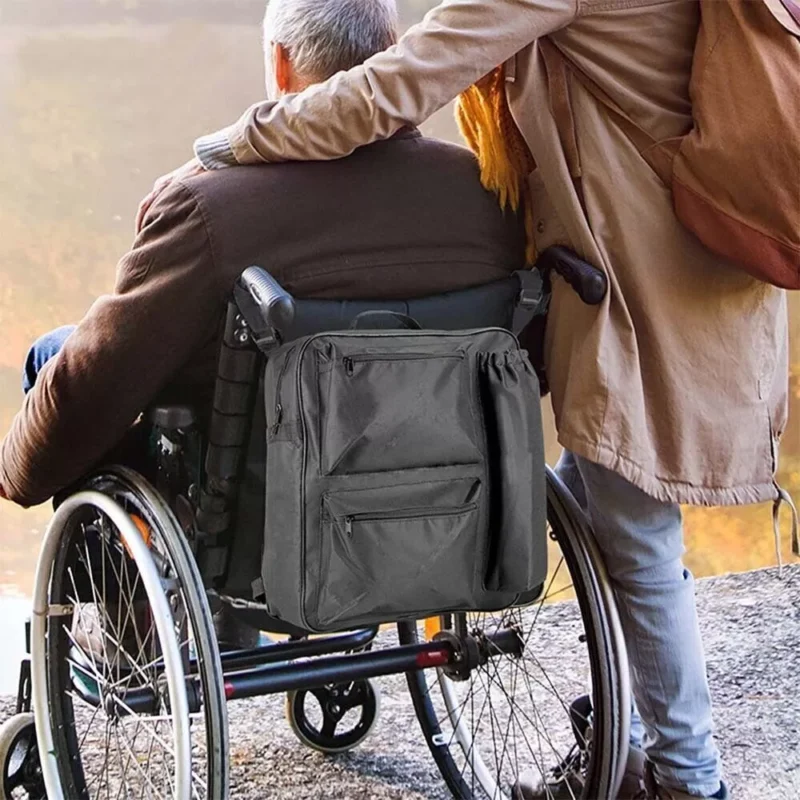 Black shopping bag attached to a wheelchair with a person sitting.
