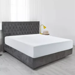 Bed with a white waterproof mattress protector in a modern bedroom.