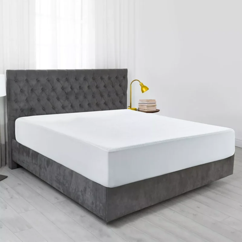 Bed with a white waterproof mattress protector in a modern bedroom.
