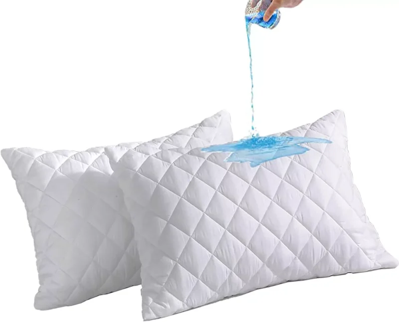 Two white quilted pillows with blue liquid being poured on them.