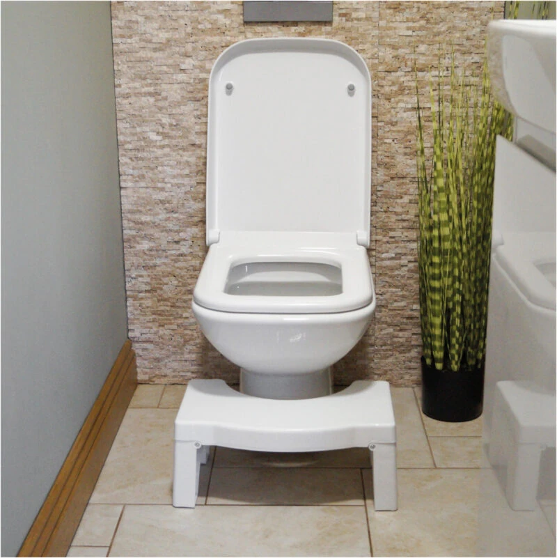 Toilet squat stool placed in front of a toilet in a bathroom.