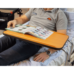 Person using a hospital overbed table while reading a magazine.