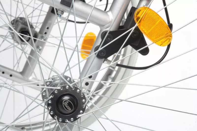 Close-up of a wheelchair's rear wheel with spokes and reflectors.