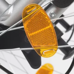 Close-up of an orange reflector on wheelchair spokes.