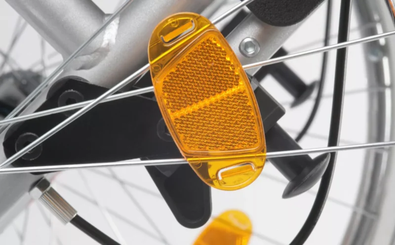 Close-up of an orange reflector on wheelchair spokes.
