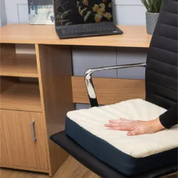 Gel seat cushion on a black office chair with a hand pressing it.