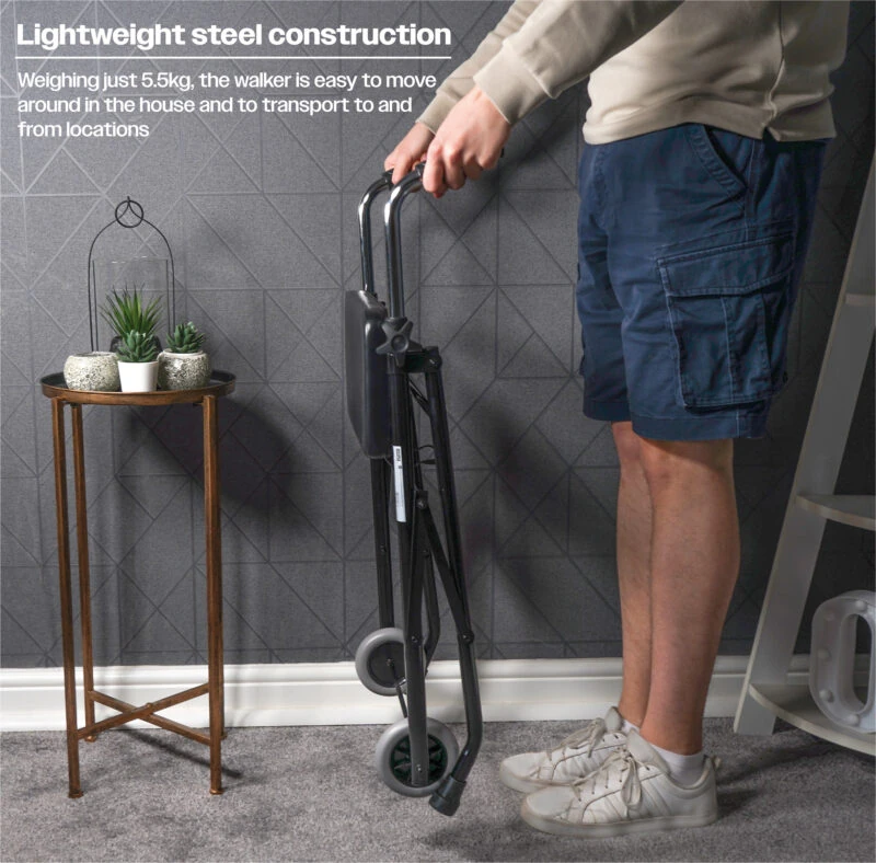 Person holding a folded wheeled walker next to a small table with plants.
