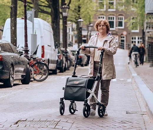 Person using Rollz Flex Shopper rollator on a cobblestone street.