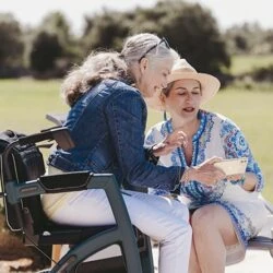 Two women sitting outdoors, one on a Rollz Motion Performance walker.