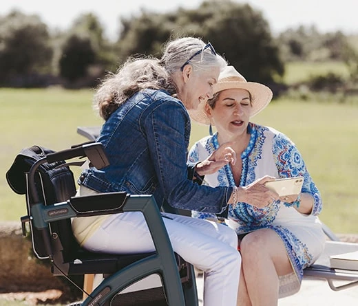 Two women sitting outdoors, one on a Rollz Motion Performance walker.