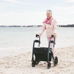 Person using Rollz Motion Rhythm Rollator on a sandy beach.