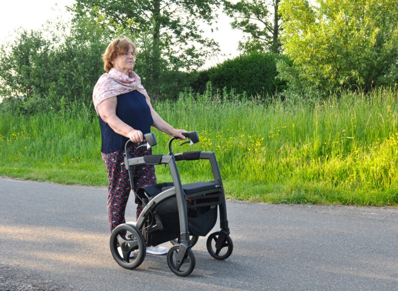 Person using the Rollz Motion Rhythm Rollator on a paved path.