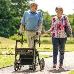 Two people walking outdoors with a Rollz Motion Rhythm Rollator.