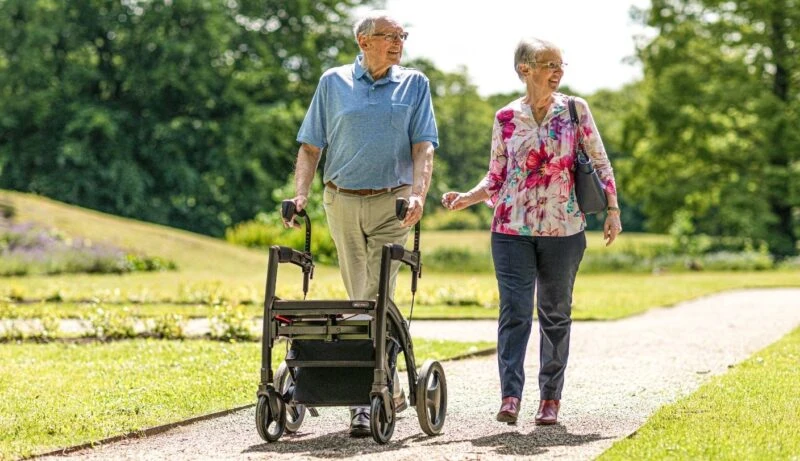 Two people walking outdoors with a Rollz Motion Rhythm Rollator.