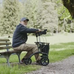 Man sitting on a bench with a Saljol Allround Crossover Rollator beside him.