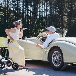 Woman with Saljol Carbon Rollator next to a vintage car on a sunny day.
