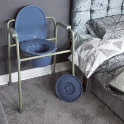Bedside commode with flip-up seat and lid next to a bed.