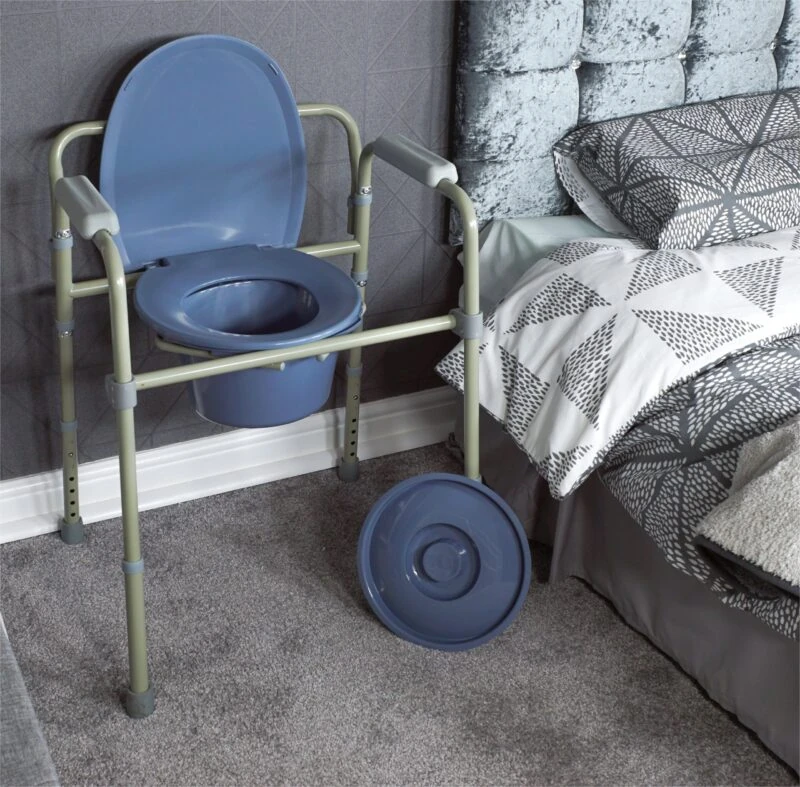 Bedside commode with flip-up seat and lid next to a bed.